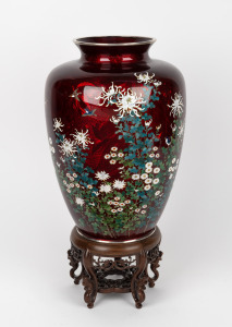 A Japanese pigeon blood cloisonne vase with chrysanthemum decoration and carved timber base, early to mid 20th century. Note: Base drilled at some stage for lamp conversion. 42cm high overall.