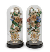 A pair of antique French cylindrical glass domes on ebonized timber bases housing floral displays, 19th century, 50cm high, bases 20cm diameter.
