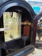 An antique English spring table clock in ebonized fruitwood case with brass bound single pad top and bail carrying handle, fish scale sound frets, standing on bracket feet. Original convex painted enamel dial with Roman numerals and maker's details "ARCH' - 4