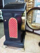 An antique English spring table clock in ebonized fruitwood case with brass bound single pad top and bail carrying handle, fish scale sound frets, standing on bracket feet. Original convex painted enamel dial with Roman numerals and maker's details "ARCH' - 5