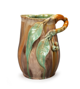 REMUED green and brown glazed pottery jug with orange highlights, adorned with branch handle, gumnuts and leaves, incised "Remued, Hand Made, 189M", 21.5cm high