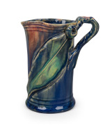 REMUED&nbsp;blue glazed pottery jug with applied gumnut, leaf and branch handle, incised "Remued", 14cm high