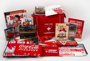 Sydney Swans cooler bag containing an assortment of more than forty mostly Swans-branded items (DVDs, magazines, Matchbox car), plus some AFL Centenary-branded items (Matchbox cars, quiz cards).