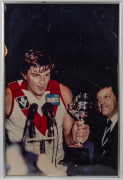 Two framed photographs of Barry Round winning the 1982 Escort Cup with Alan Aylett in background, 52.5 x 70.5cm overall, plus 'September 24th 2005 AFL Grand Final Sydney Swans versus West Coast Eagles' photo montage, framed and window mounted, 56 x 43cm o - 2