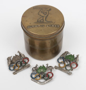 1956 MELBOURNE OLYMPICS: Brass cannister made by Stokes & Sons of Melbourne; together with three assorted brooches, (4 items), the cannister 8cm high