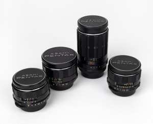 ASAHI KOGAKU: Group of four M42 Super-Takumar lenses, each with Pentax front and rear lens caps - one 24mm f3.5, one 28mm f3.5, one 50mm f1.4, and one 150mm f4. (4 items)
