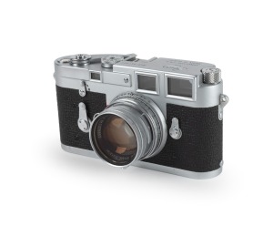 LEITZ: Single-stroke Leica M3 rangefinder camera [#951991] with Summicron 50mm f2 lens [#1378853], Leitz UVa lens filter, Leica leather case, flash sync plugs, and instruction booklet, c. 1959.