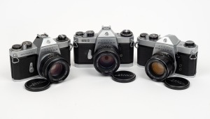 ASAHI KOGAKU: Group of three cameras with Asahi Pentax lens caps - one Pentax SP500 with Super-Takumar 55mm f2 lens, one Pentax SPII with SMC Takumar 55mm f1.8 lens, and one Pentax ESII with SMC Takumar 50mm f1.4 lens. (3 items)