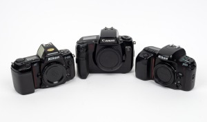 VARIOUS MANUFACTURERS: Group of three SLR camera bodies with body caps - one Canon EOS 5, one Nikon F50, and one Nikon F-801. (3 items)