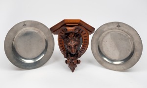 A pair of antique pewter dinner plates with engraved crest of the McDonell or Glengarry clan; together with an attractive antique oak wall bracket with carved fox motif, 19th century, (3 items), the plates 25cm diameter