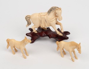 Three Chinese carved ivory horse statues, one on carved timber base, early to mid 20th century, ​​​​​​​the largest 8cm high overall.