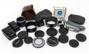 MINOLTA: Accumulation of twenty-four photography accessories, comprising three metal lens hoods, ten lens caps, six leather pouches, one AC 1B Skylight lens filter in case, one BH-70L Battery Holder in maker's box, one Minoltina remote control, one access