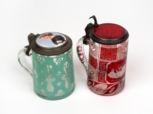 Two antique Bohemian overlay glass beer steins, one example in ruby with wheel engraved decoration and pewter mounts, the other in green with attractive hand-painted porcelain top mounted in pewter, circa 1850s, 17cm and 13cm high