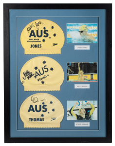 AUSTRALIA AT THE 2003 WORLD AQUATICS CHAMPIONSHIPS, BARCELONA: A framed display featuring swimming caps signed by Australian medallists LIESEL JONES, MATT WELSH and PETRIA THOMAS together with photographs of each swimmer. Overall 76 x 59cm.