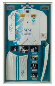 SYDNEY 2000 OLYMPIC TORCH RELAY: A framed and glazed display comprising the torch, relay clothing, various photographs and plaques associated with the participation of Maltese-born Queenslander Paul Michael Lapira, who at the age of seventy-three was a pr
