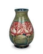 MOORCROFT "Waratah" baluster shaped English pottery vase on blue and green ground, impressed signature cartouche "W. Moorcroft, Potter to H. M. The Queen. Made in England" with underglazed blue signature mark "W. Moorcroft", 25cm high