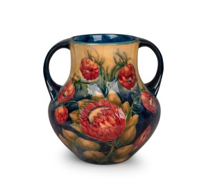 MOORCROFT "Protea" rare twin-handled English pottery vase, finely decorated with large protea flowers and the reverse decorated with a spray of African Lilies, circa 1928, impressed signature mark to base "W. Moorcroft, Potter to H. M. The Queen. Made in 