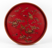 An antique Japanese red lacquered serving tray with hand painted birds and blossoms, Meiji Period 19th/20th century, 71.5cm diameter
