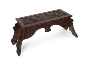 An Australian Arts & Crafts blackwood bay window seat, ornately carved with griffins and foliate decoration, early 20th century, 42cm high, 102cm wide, 40cm deep