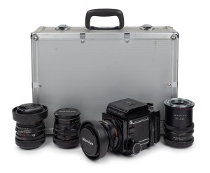 MAMIYA: RB67 SLR camera [#C558086] with Mamiya-Sekor C 90mm f3.8 lens [#107586], Mamiya lens cap, and Mamiya lens hood, c. 1970. Offered in hard case with multiple accessories including two additional lenses with front and rear lens caps, hand grip, camer