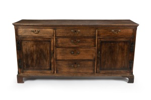 An antique English oak kitchen dresser base with cockbeaded drawers and brass swing handles, 18th/19th century, 86cm high, 170cm wide, 52cm deep.