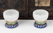 A pair of carved antique mutton jade cups on woven silk bases, housed in a blue silk lined timber box, 19th/20th century, the cups 3cm high, 5cm diameter, the case 23cm wide. - 2