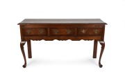 An English oak and mahogany three drawer dresser base with cabriole legs and brass swing handles, made in the Georgian style, early 20th century, 85cm high, 152cm wide, 48cm deep.