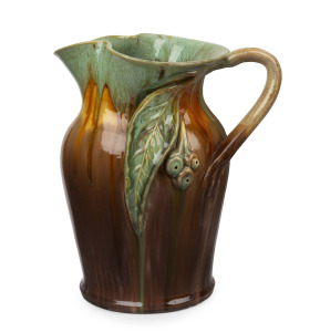 REMUED green and brown glazed pottery jug with applied gumnuts, leaf and branch handle, incised "Remued, 54LM", 25cm high