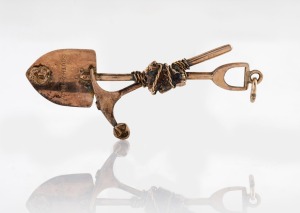 A South African 9ct gold miner's pendant with crossed pick and shovel, stamped "South Africa, 9ct", ​​​​​​​5.8cm long, 3.5 grams.