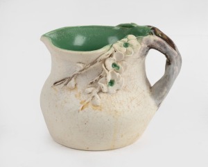 PEGGY WHITING cream and green glazed pottery jug with applied blossoms and branch handle, incised "Peggy Whiting", ​​​​​​​11cm high, 13.5cm wide.