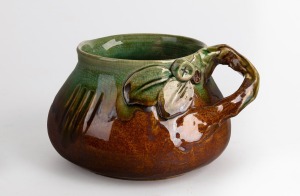 REMUED early green and brown glazed pottery jug with applied gumnuts, leaves and branch handle, with scratch mark decoration, incised "Remued", ​​​​​​​10cm high, 17cm wide.