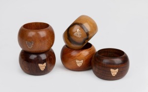 A set of five Australian timber napkin rings, each decorated with a 9ct gold map of Tasmania, early 20th century.