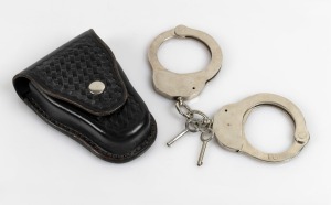 VICTORIAN POLICE issue handcuffs in original leather pouch with key, manufactured by HIATT, circa 1970, 23cm wide.