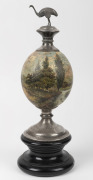 An antique hand-painted ostrich egg ornament titled "Morning", with silver plated emu finial mounted on an ebonised timber base, 19th century, A/F, 37cm high overall.