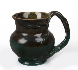 CRUFFEL green glazed porcelain jug with windswept tree and branch handle decoration, original foil label to base "Cruffel Art Porcelain, Melbourne", 16cm high.