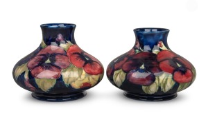 MOORCROFT pair of "Pansy" pattern pottery vases on blue ground, impressed "Moorcroft, Made In England" with underglazed blue initials "W.M.", 10​​​​​cm high, 13cm wide.