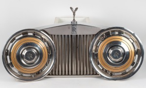 ROLLS ROYCE vintage car grill with Charles Sykes SPIRIT OF ECSTACY car mascot attached, together with two Rolls Royce hubcaps, ​​​​​​​the grill 69cm wide.