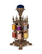 An antique American cast metal spool holder with pin cushion top and assorted threads, 19th/20th century, 25cm high.