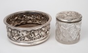 A sterling silver wine bottle coaster; together with an antique Chorus of Angels sterling silver topped vanity jar, 19th century, (2 items), the coaster 6cm high, 15cm diameter.