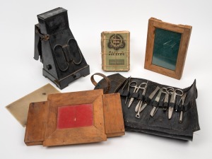 An antique surgical field kit in leather swag; together with an antique darkroom light and some slide accessories.