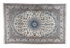 A Persian hand-knotted rug on cream ground with blue highlights. Note: Some staining throughout. 303 x 198cm.