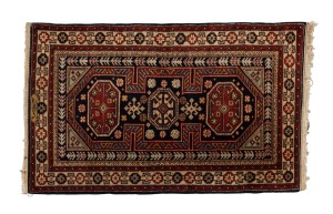 A hand-knotted Persian rug on black and burgundy ground, signed lower centre, 130 x 79cm.