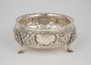 An antique English sterling silver bowl with floral repousse decoration resting on three pad feet with facemask adornments, by Charles Engelhard of London, circa 1881, 5.5cm high, 13cm wide, 166 grams.
