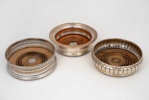 Three assorted antique and vintage sterling silver wine bottle coasters, 19th/20th century, the largest 14cm diameter, 610 grams total (including timber bases).