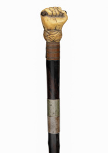 An antique poacher's walking stick with rosewood veneered shaft, finely carved whale's tooth fist grip and silver collar engraved "Load Me Well & Keep Me Clean, & When I Strike I Make A Scene" with owner's initials below "J.M.M.", 19th century, 86cm long.