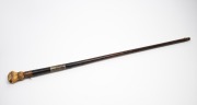 An antique poacher's walking stick with rosewood veneered shaft, finely carved whale's tooth fist grip and silver collar engraved "Load Me Well & Keep Me Clean, & When I Strike I Make A Scene" with owner's initials below "J.M.M.", 19th century, 86cm long. - 2