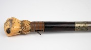 An antique poacher's walking stick with rosewood veneered shaft, finely carved whale's tooth fist grip and silver collar engraved "Load Me Well & Keep Me Clean, & When I Strike I Make A Scene" with owner's initials below "J.M.M.", 19th century, 86cm long. - 3