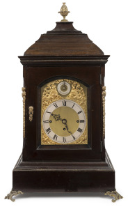 A monumental antique English three train spring table clock, circa 1910. Mahogany inverted bell top case decorated with ormolu mounts, caryatids to the cantered corners and pineapple finial. Shallow arch brass dial plate with applied wing to cherub spandr