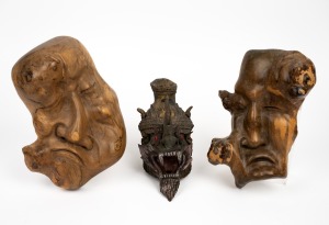 A terracotta demon face mask with hand-painted finish (A/F); together with an unusual pair of carved wooden grotesque face masks, 20th century, (3 items), the largest 26cm high.