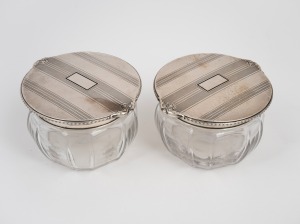 A beautiful pair of antique sterling silver and enamel topped crystal vanity jars with fine wheel cut floral decoration, early 20th century, stamped "STERLING SILVER, HAND HAMMERED", 7.5cm high, 12.5cm wide, 154 grams silver weight (not including crystal).